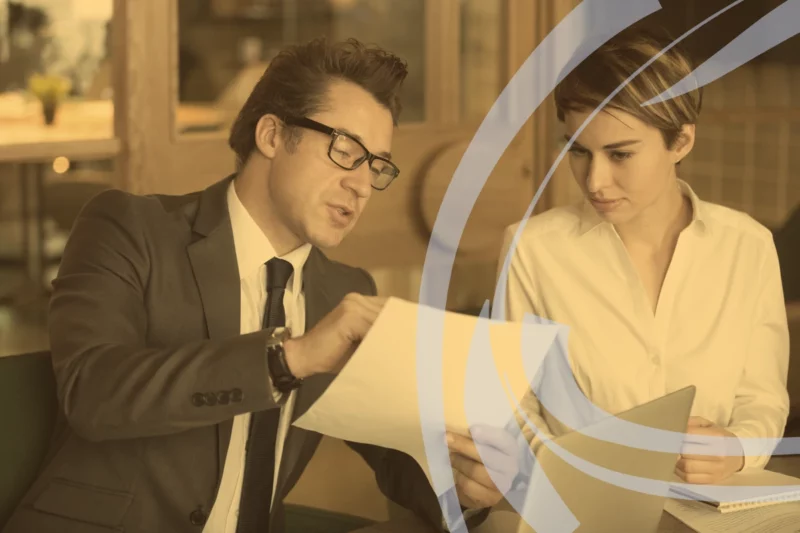 Small business consultant explaining a contract to a client, with a warm amber tone and swirl logo overlay